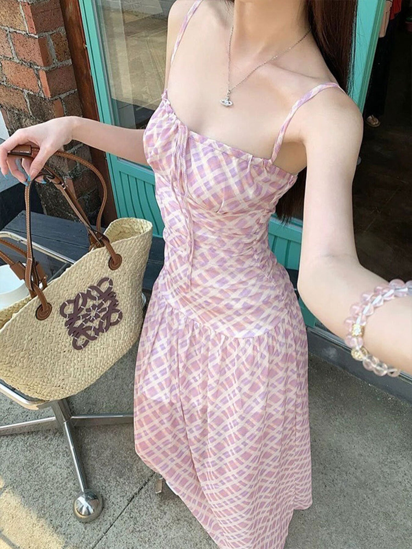 Woman wearing a pink dress with a straw bag in the background