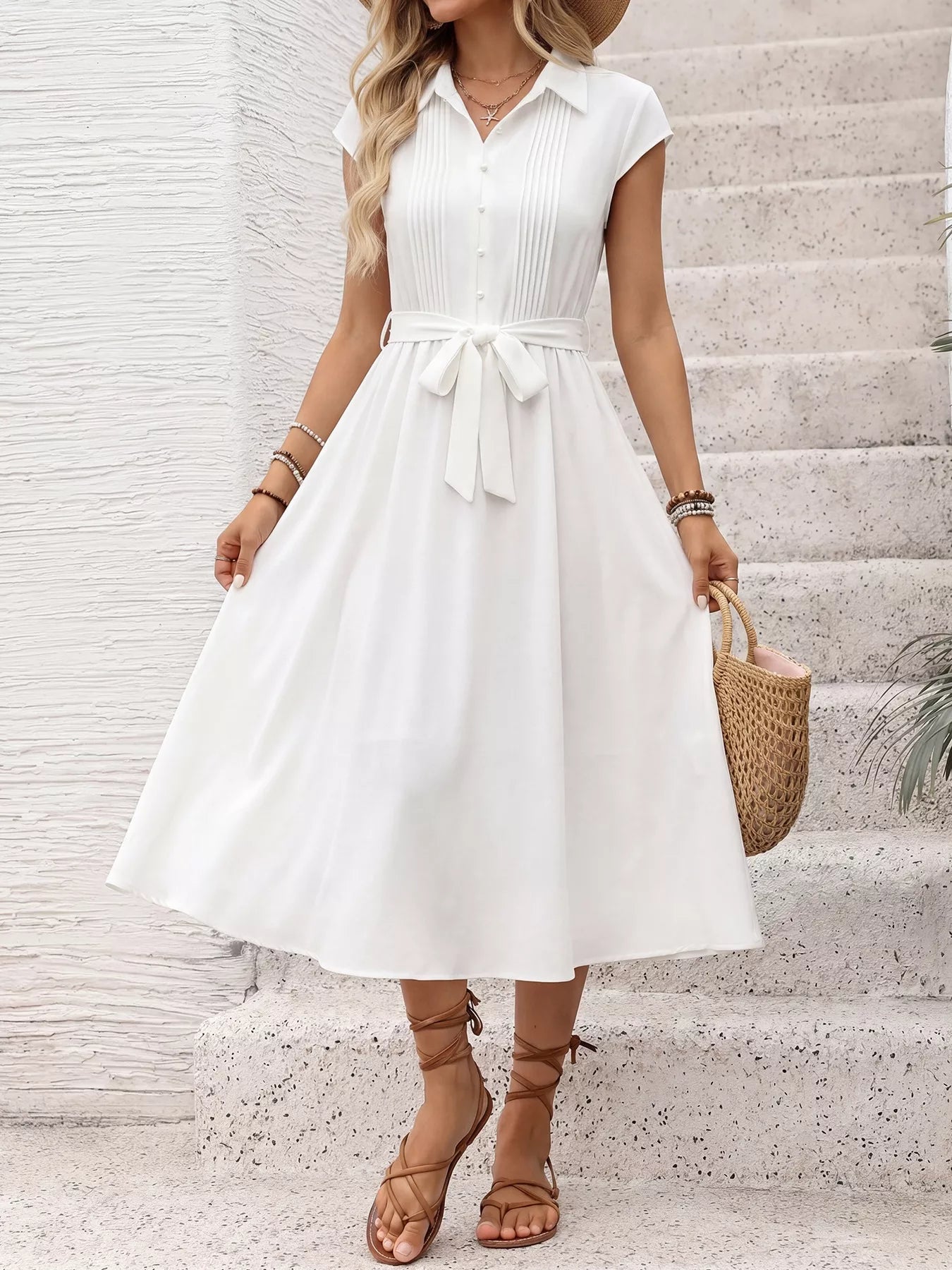 Woman wearing a white dress with a belt, standing on a staircase.