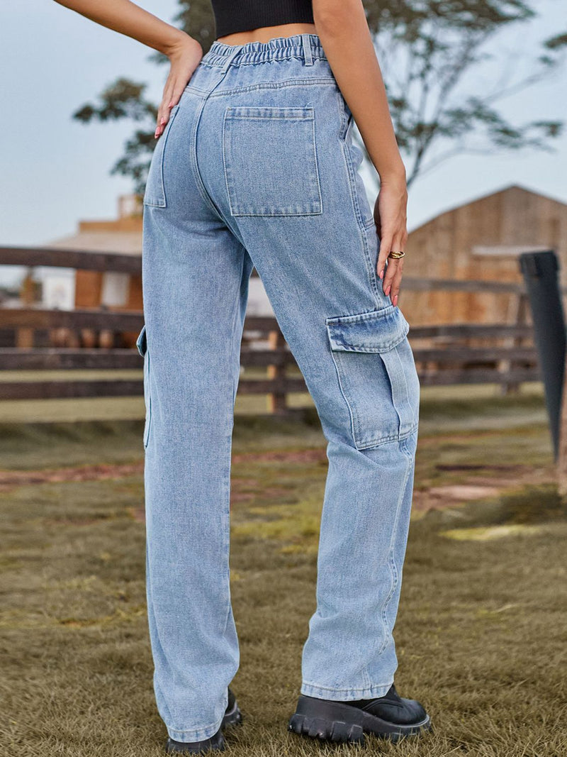Person wearing light blue cargo pants standing outdoors with a wooden fence and trees in the background.