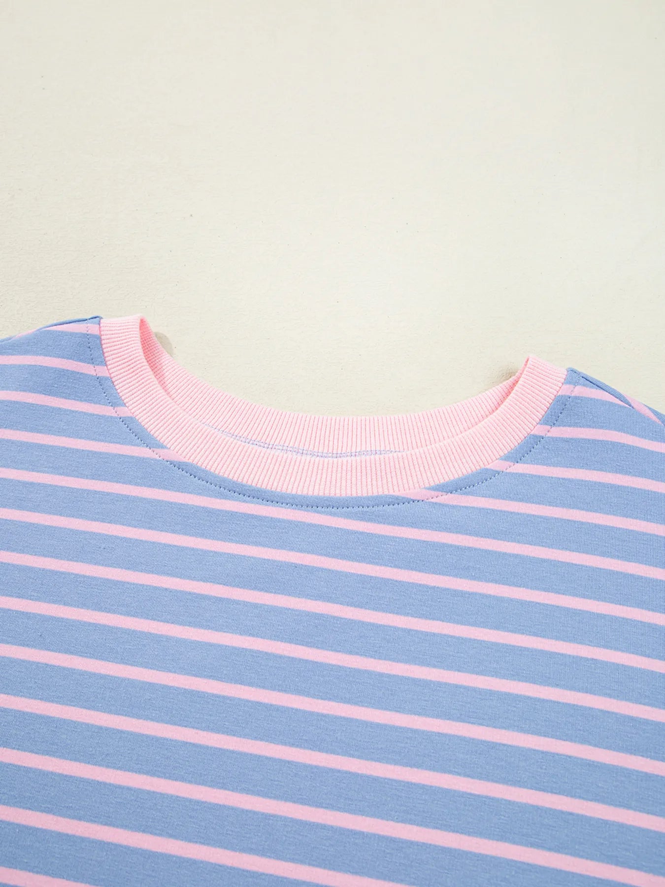 Close-up of a blue and pink striped shirt with a light green background
