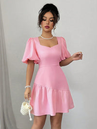Woman wearing a pink dress with puffed sleeves against a plain background