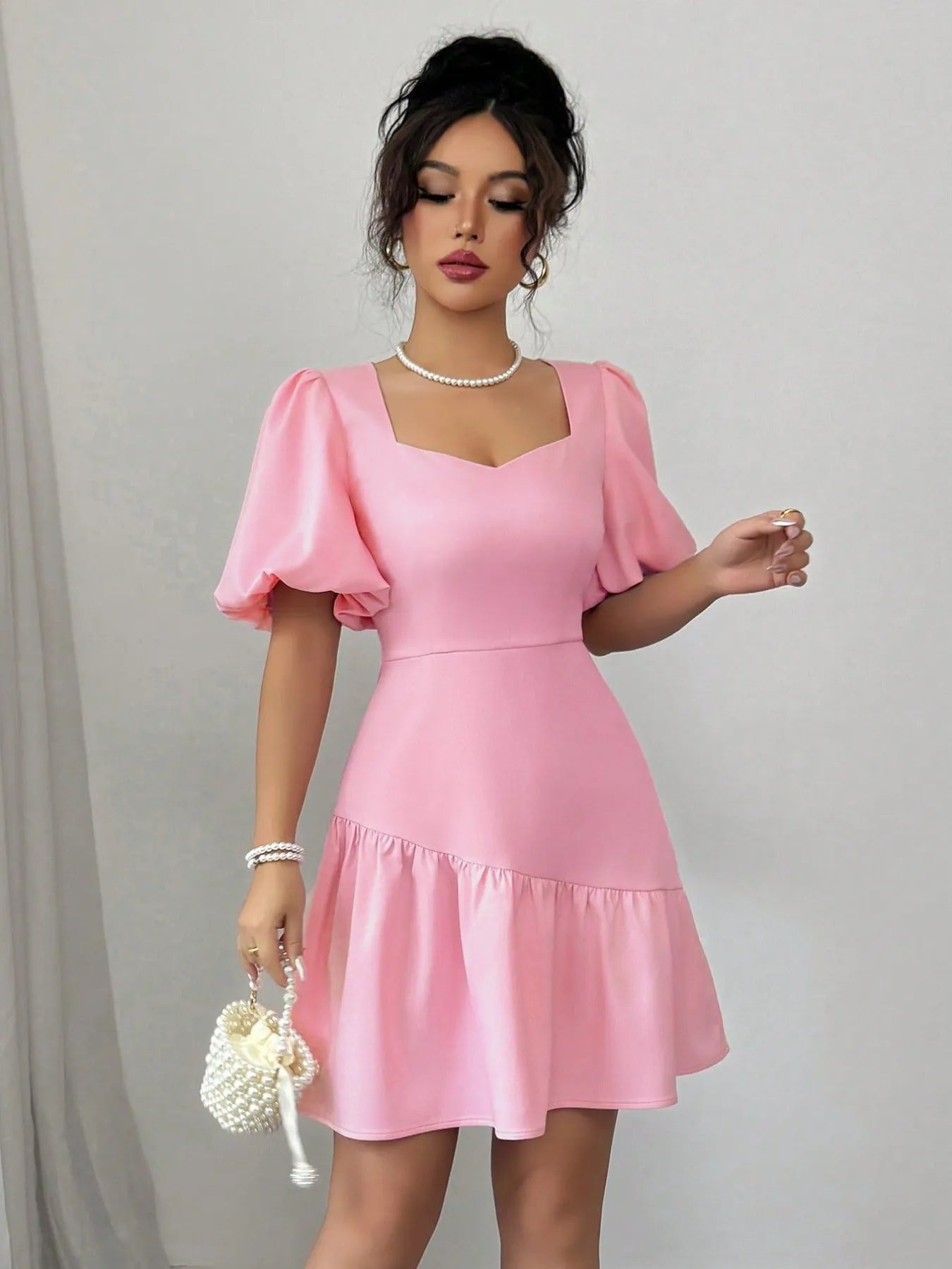 Woman wearing a pink dress with puffed sleeves against a plain background