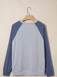 Gray and blue sweatshirt on a wooden hanger against a beige background