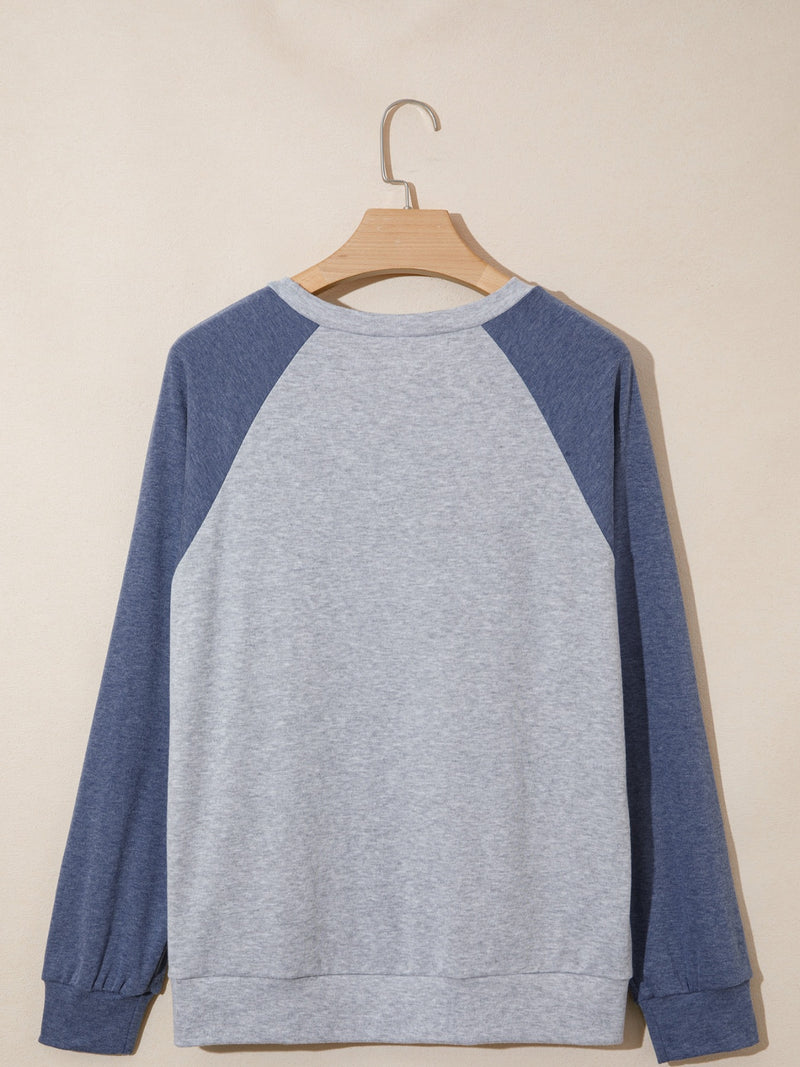 Gray and blue sweatshirt on a wooden hanger against a beige background