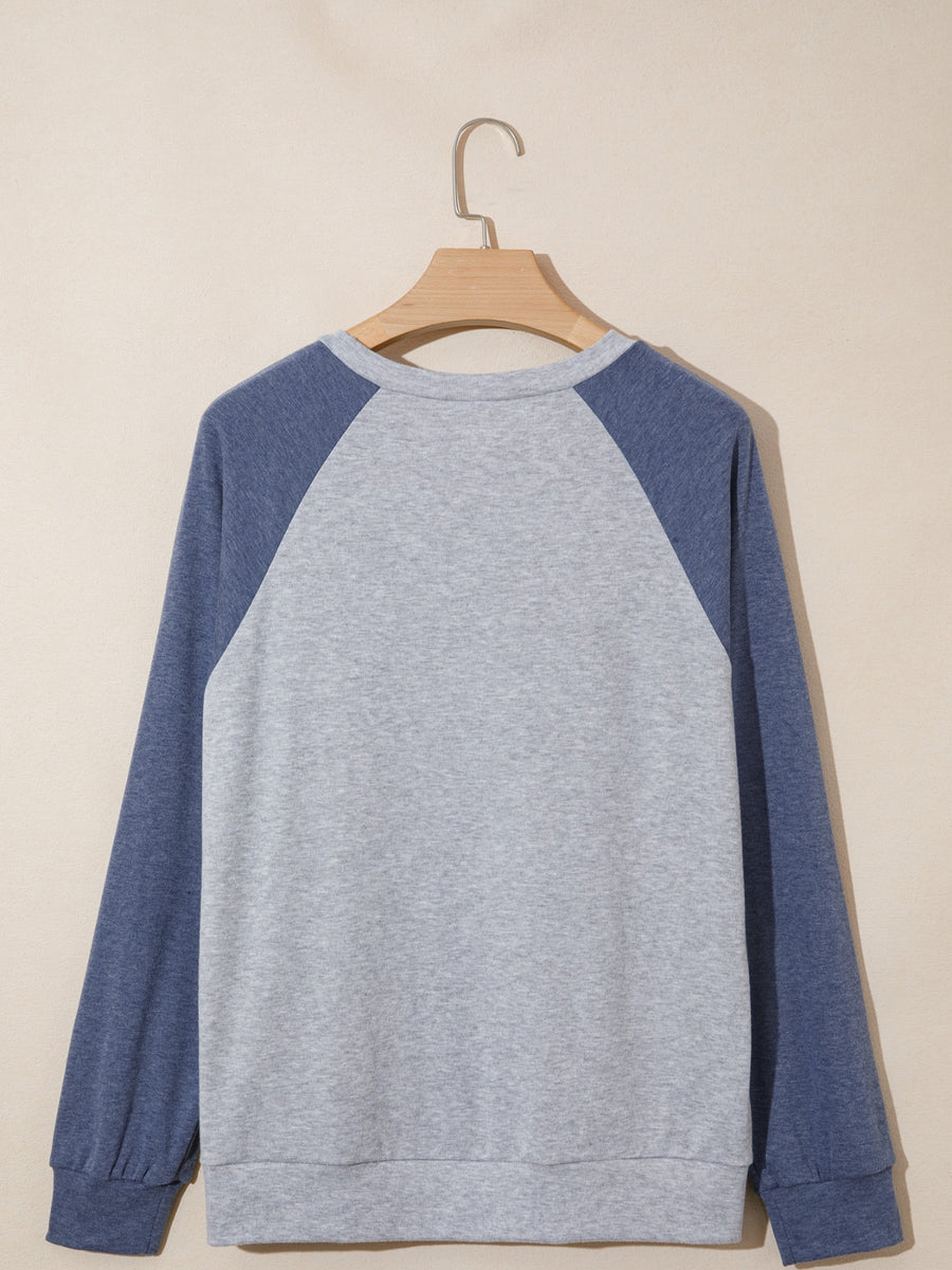Gray and blue sweatshirt on a wooden hanger against a beige background