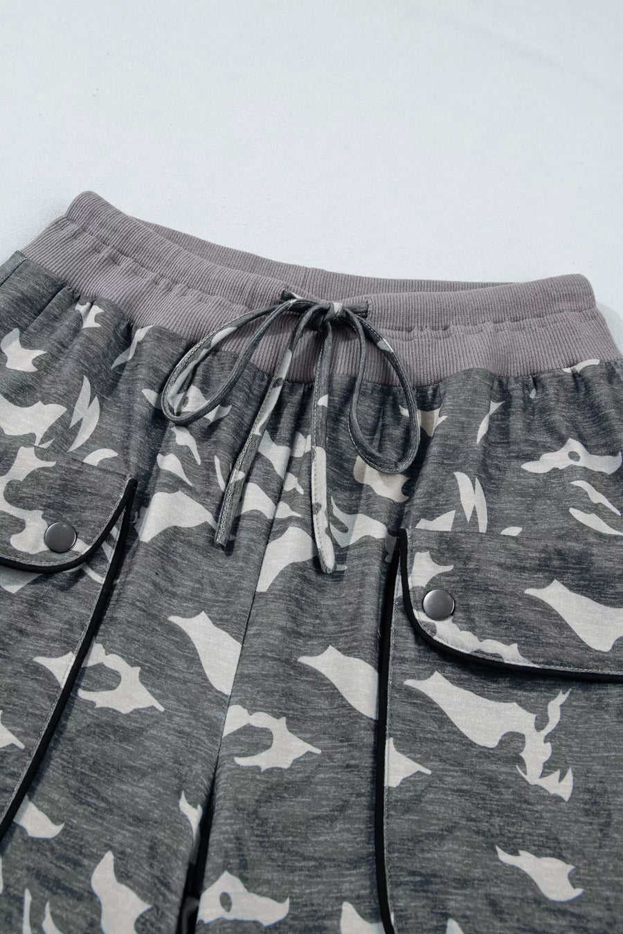 Gray camouflage pants with drawstring on a light gray background