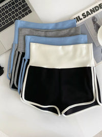 Four pairs of shorts in black, white, gray, and blue on a desk.