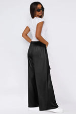 Woman wearing a white top and black wide-leg pants on a white background
