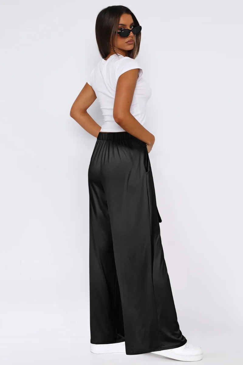 Woman wearing a white top and black wide-leg pants on a white background