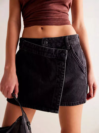 Person wearing a black denim skirt and maroon top against a neutral background