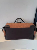Brown and black duffel bag on a light surface with a neutral background