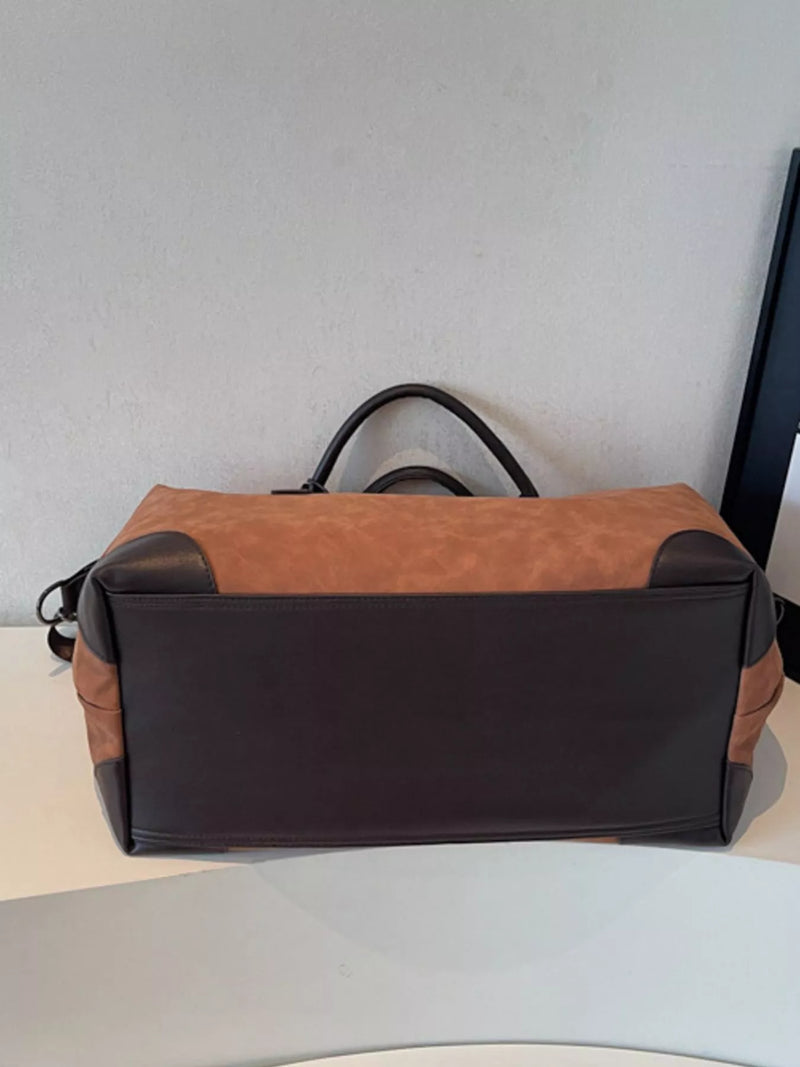 Brown and black duffel bag on a light surface with a neutral background