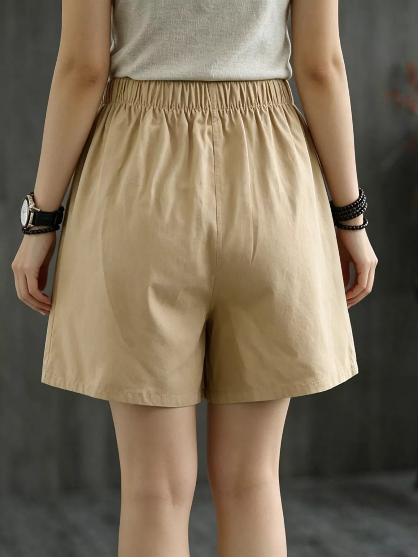 Beige shorts worn by a person on a dark background