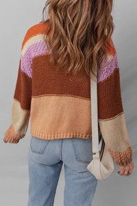 Person wearing a colorful striped sweater and blue jeans, holding a beige bag.