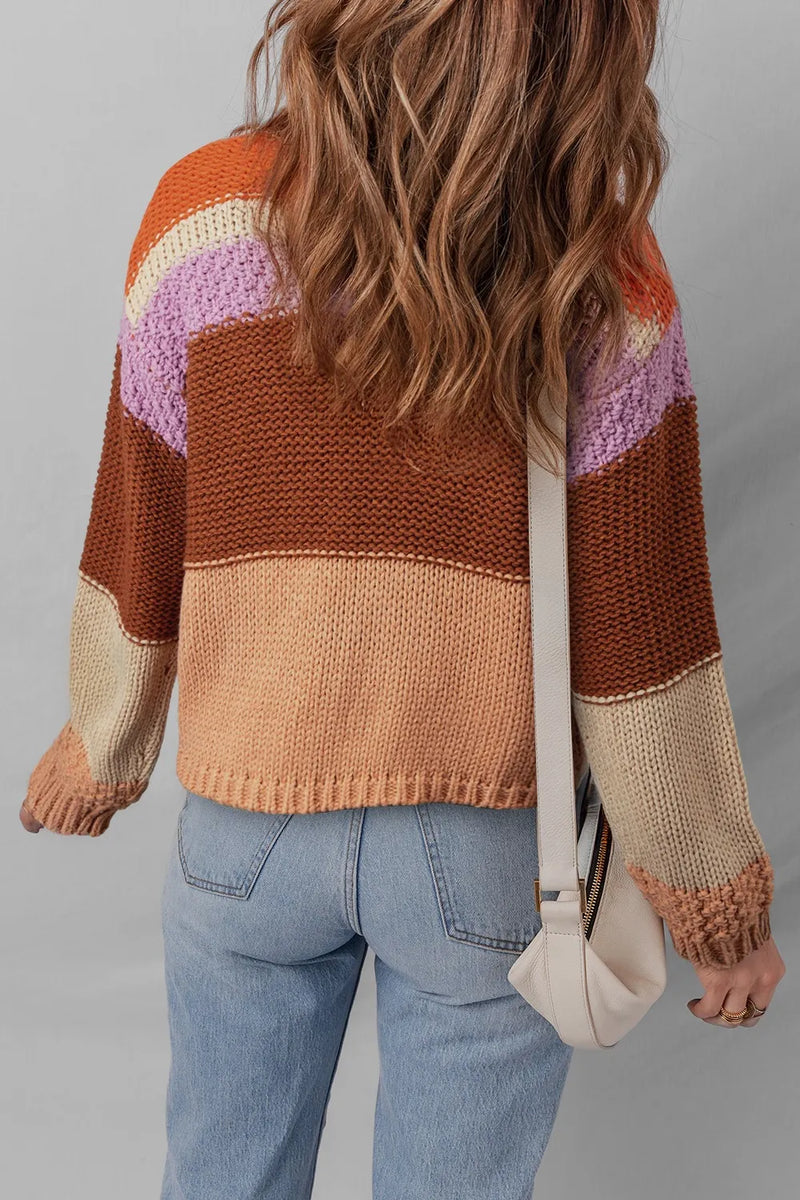 Person wearing a colorful striped sweater and blue jeans, holding a beige bag.