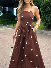 Woman wearing a brown dress with white polka dots outdoors.