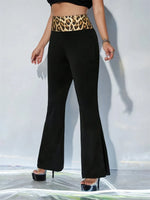 Person wearing black flared pants with a leopard print belt against a white background
