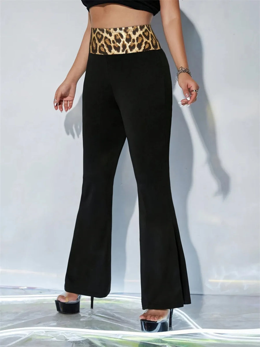 Person wearing black flared pants with a leopard print belt against a white background