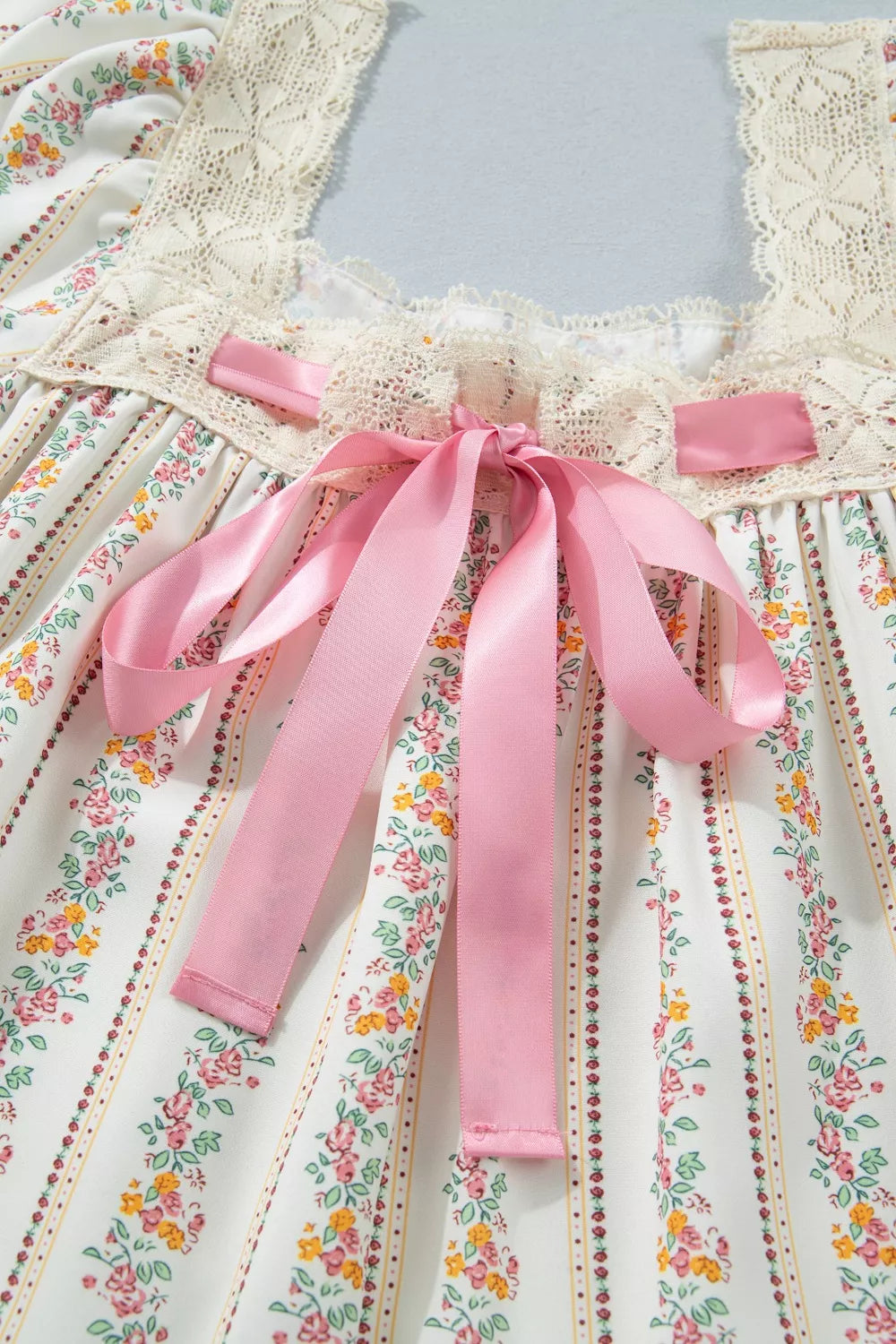 Floral dress with a pink ribbon on a light gray background