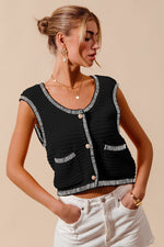 Woman wearing a black sleeveless top with white trim on a beige background