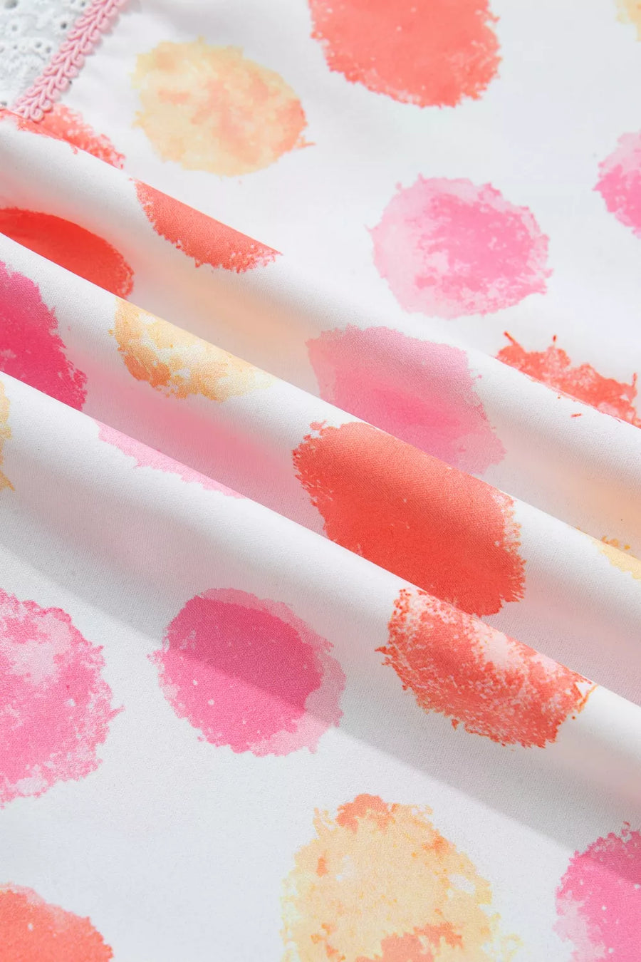 Close-up of fabric with colorful watercolor-like dot pattern on a white background
