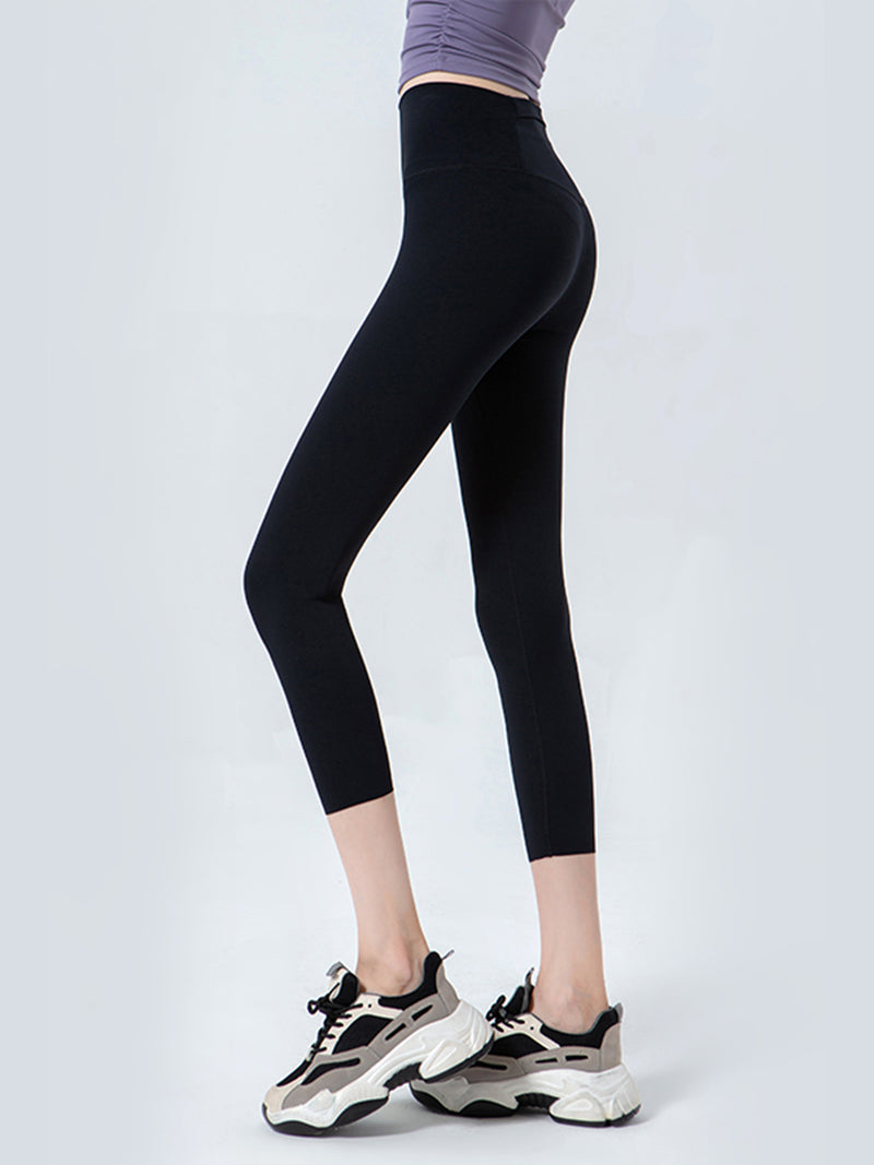 Person wearing black leggings and white sneakers on a light gray background