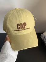Beige cap with 'GAP' logo held by a person against a neutral background