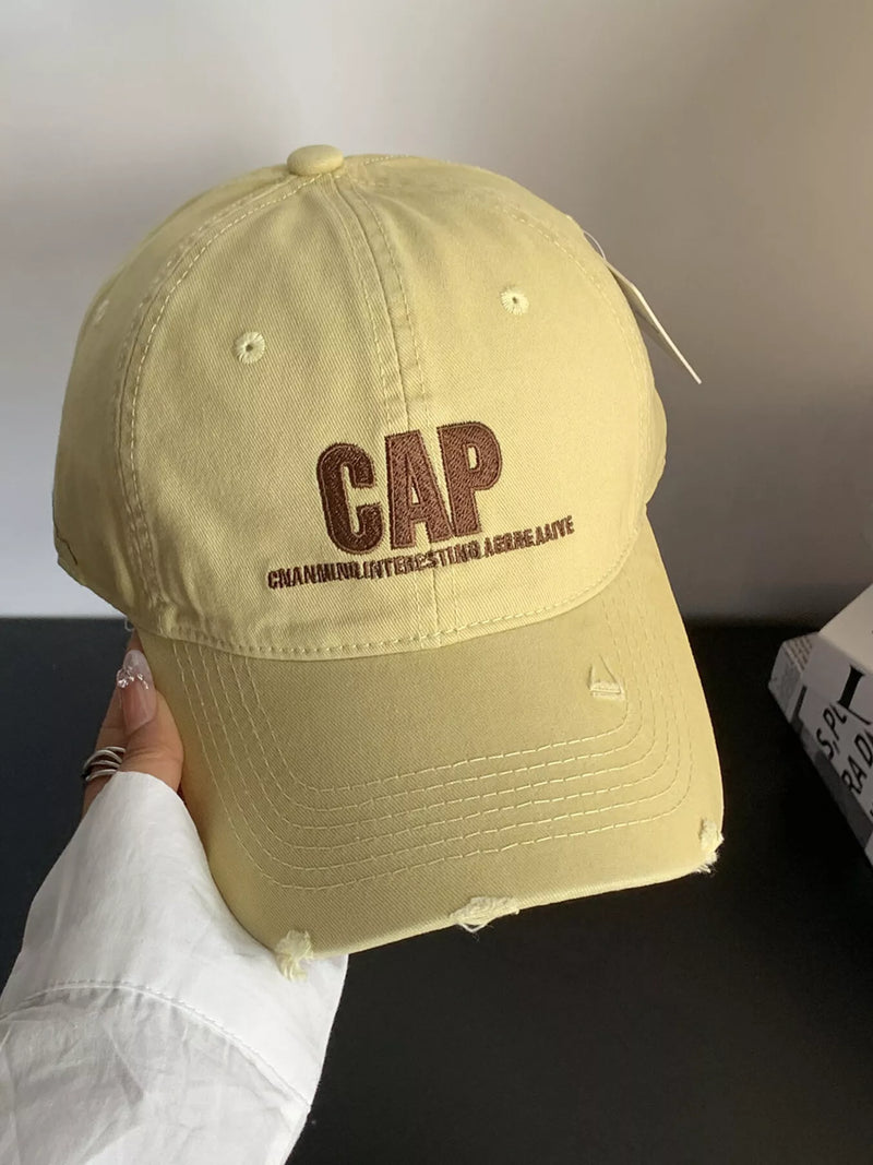 Beige cap with 'GAP' logo held by a person against a neutral background