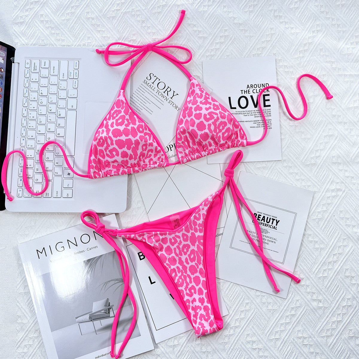 Pink leopard print bikini set on a white surface with magazines underneath