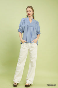 Woman wearing a blue blouse and white pants on a green background