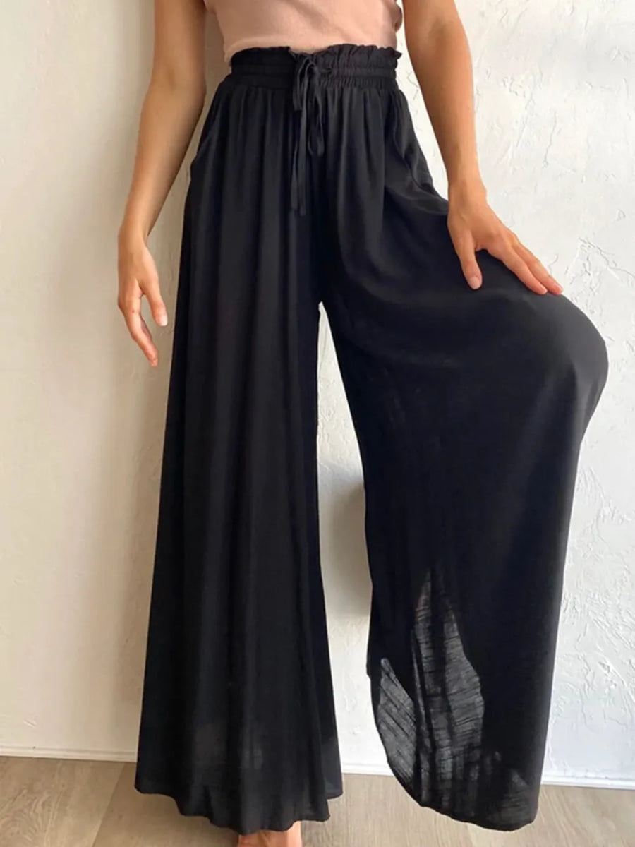 Person wearing black wide-leg pants against a neutral background