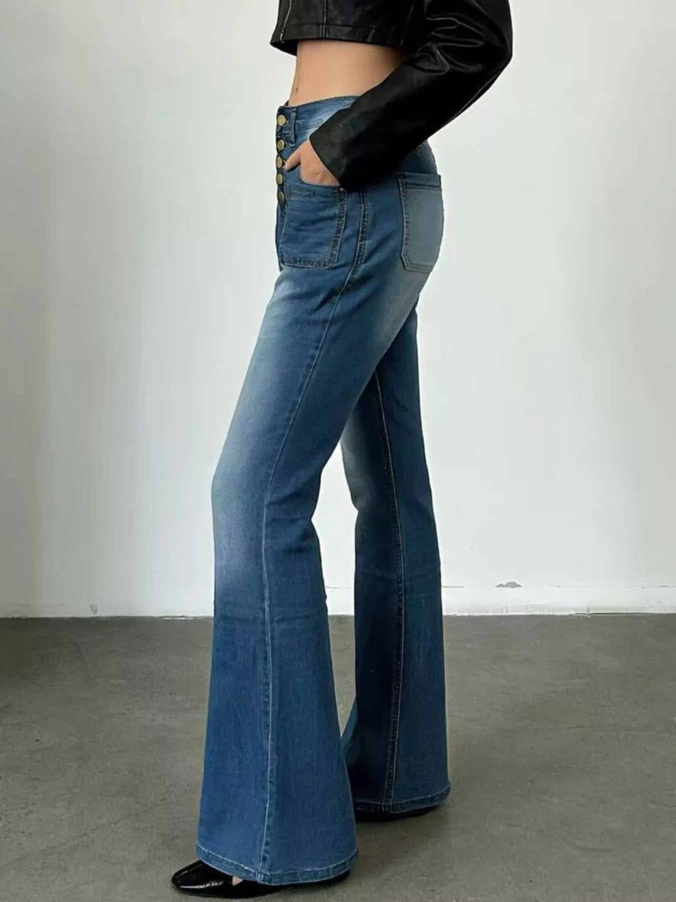 Person wearing blue flared jeans with a plain background