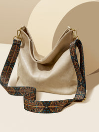 Beige handbag with a patterned strap on a beige background