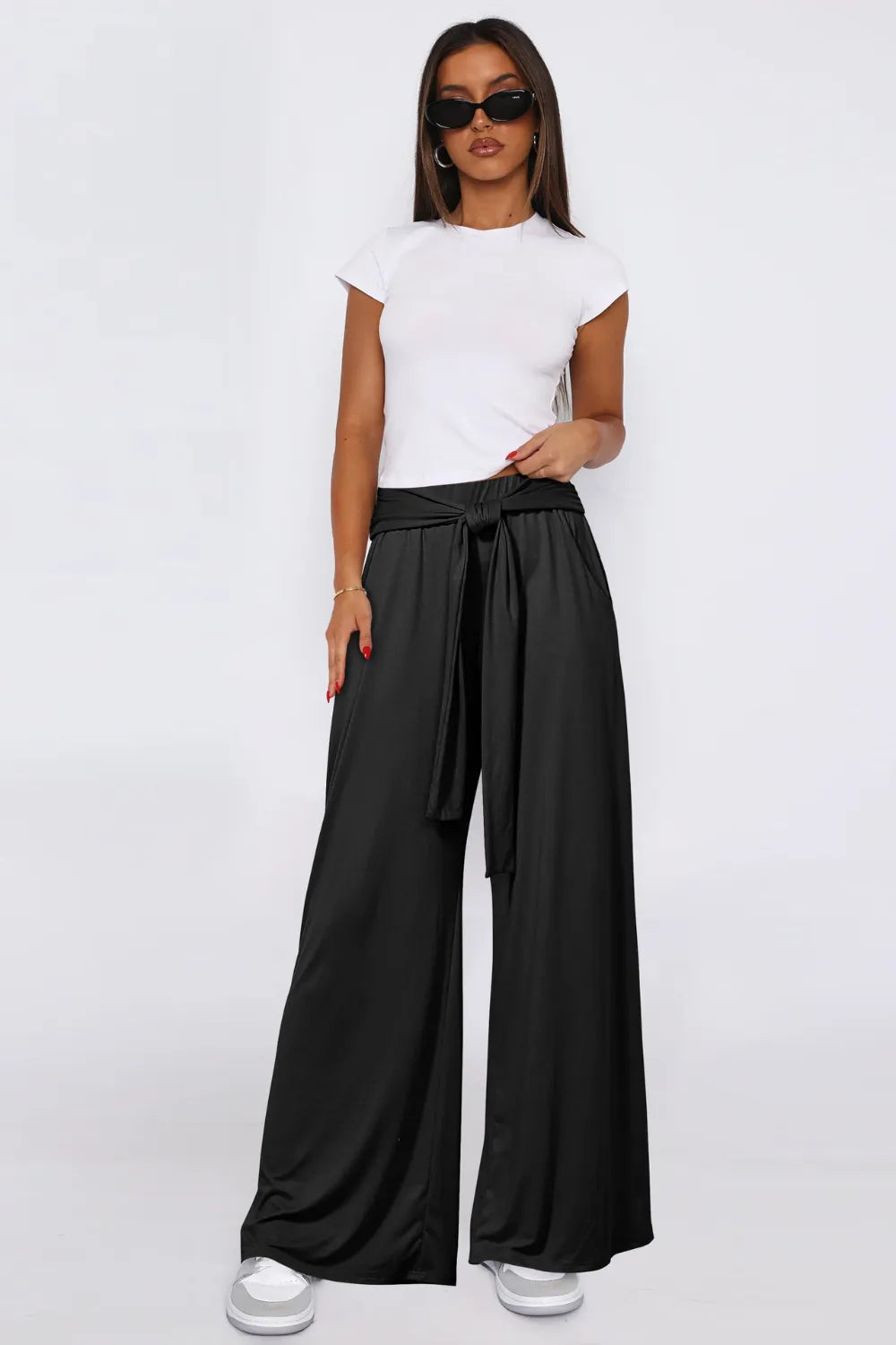 Woman wearing a white top and black wide-leg pants on a white background