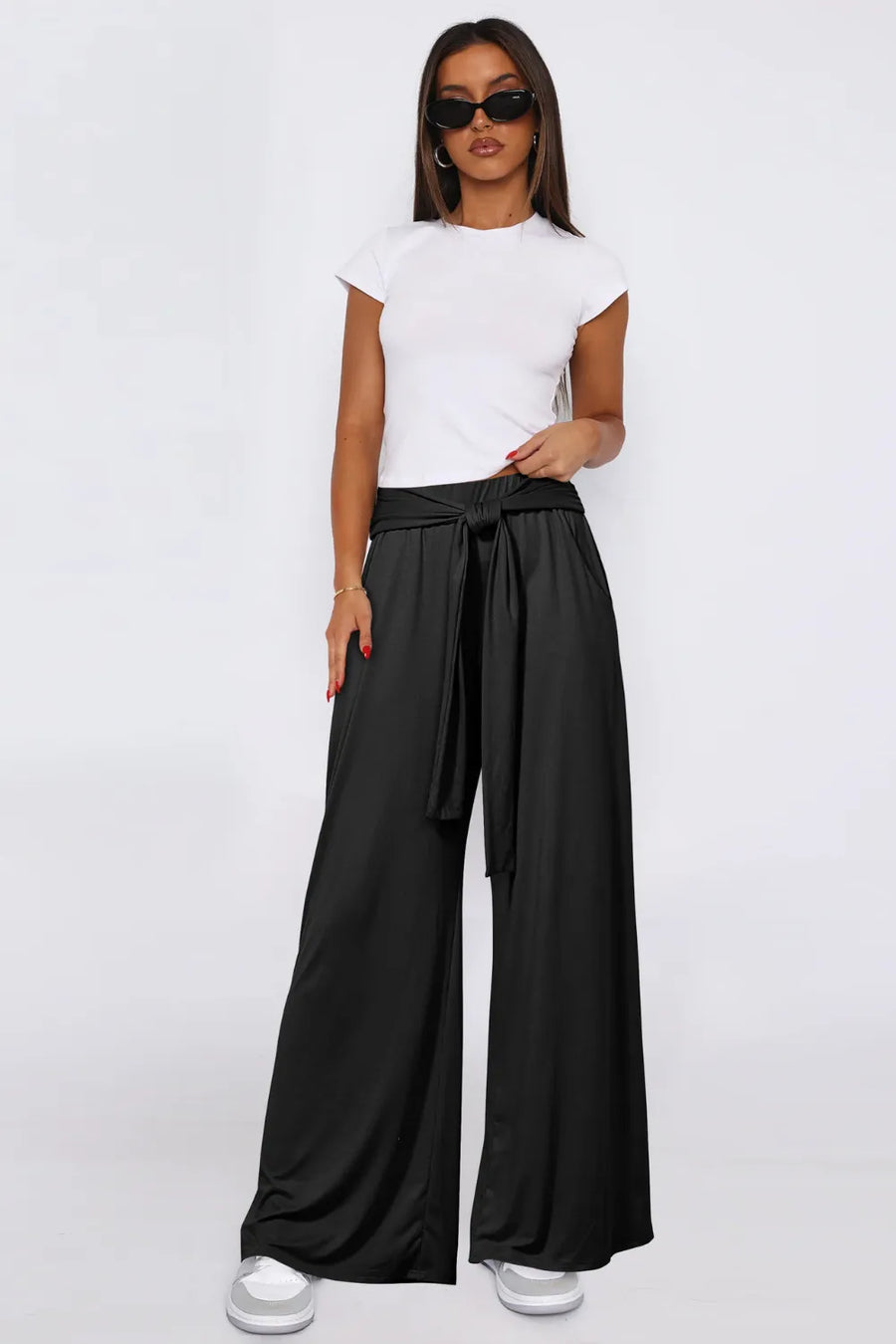 Woman wearing a white top and black wide-leg pants on a white background