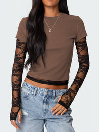 Person wearing a brown top with lace sleeves and blue jeans on a white background