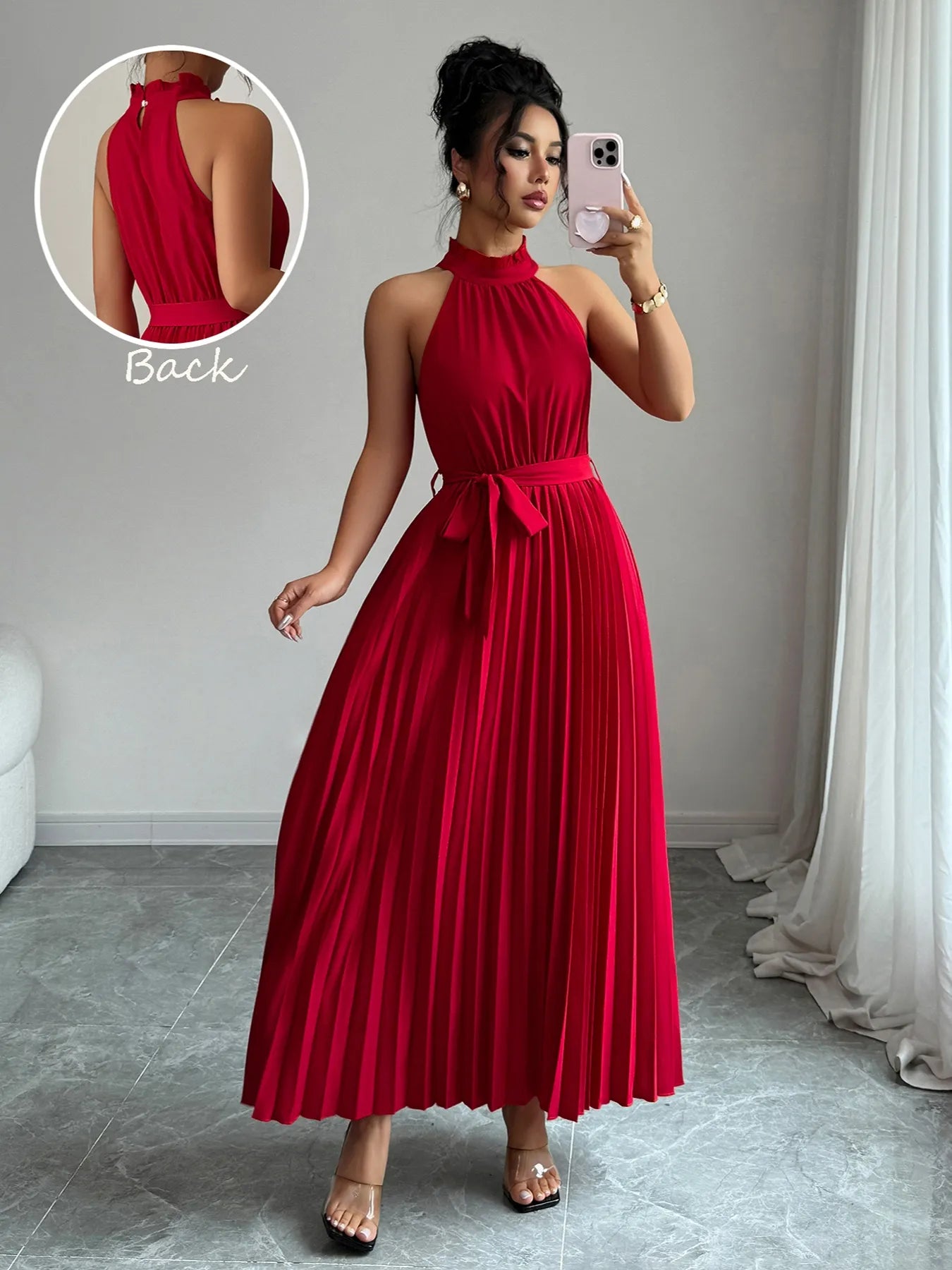 Woman wearing a red halter neck dress taking a mirror selfie.