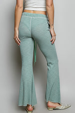 Person wearing teal flared pants on a plain background