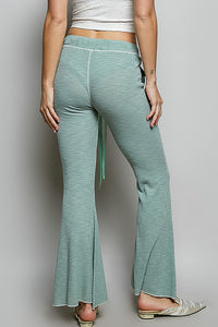 Person wearing teal flared pants on a plain background
