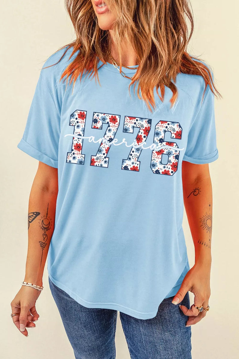 Woman wearing a light blue t-shirt with '1776' design on a beige background