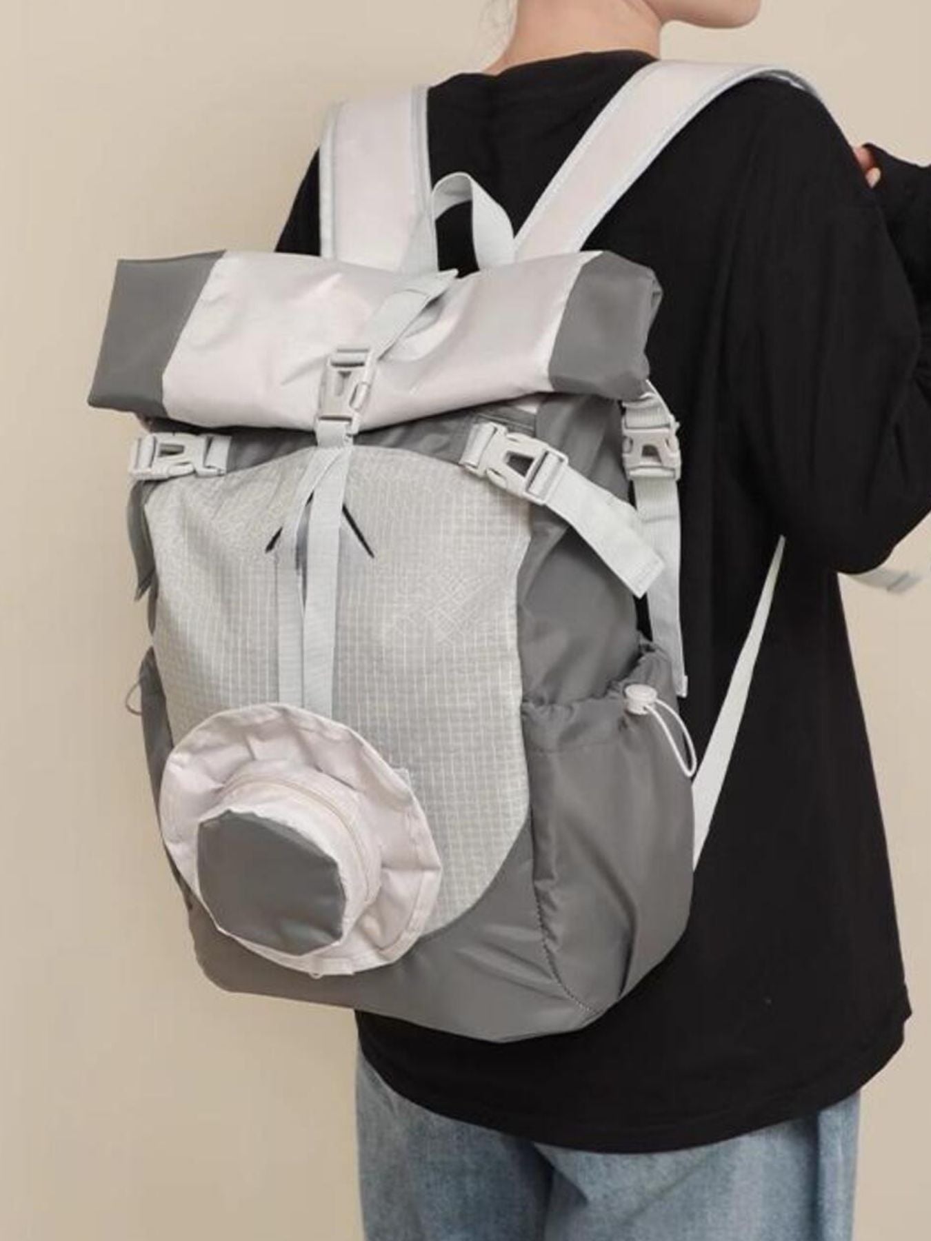 Person wearing a gray and white backpack against a plain background