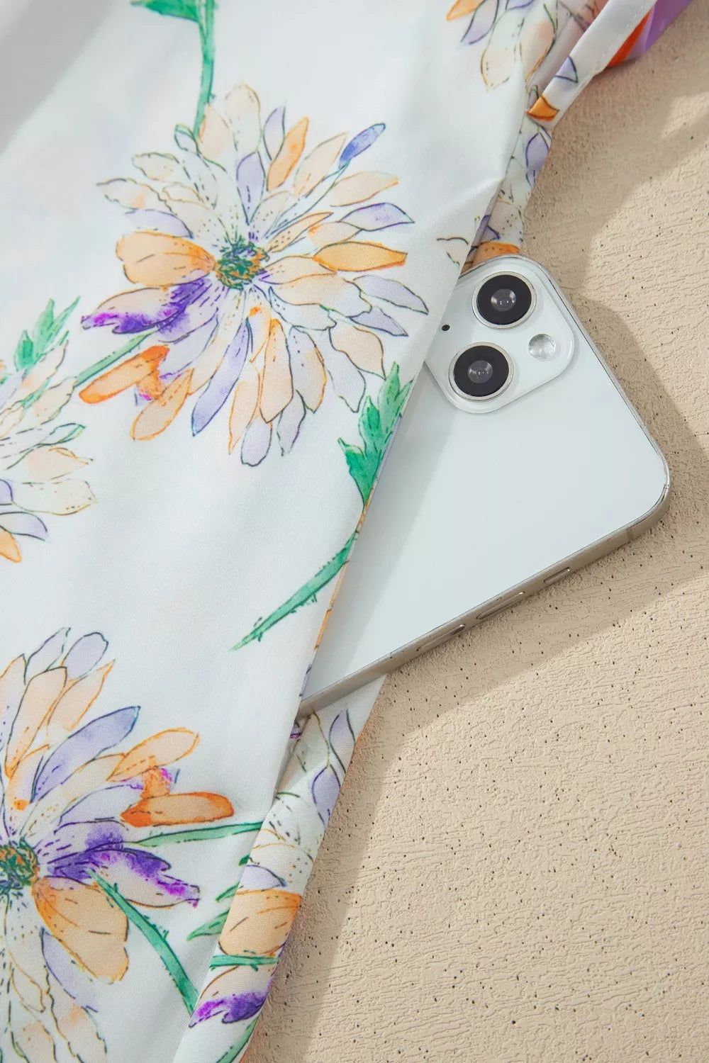 Smartphone with a floral case on a sandy surface
