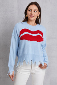 Woman wearing a light blue sweater with a red and white graphic design on a gray background