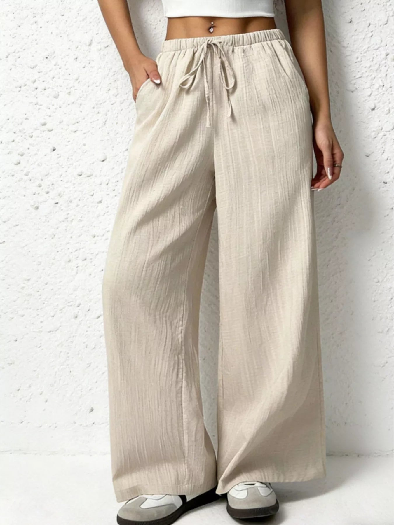 Beige wide-leg pants worn by a person on a white background