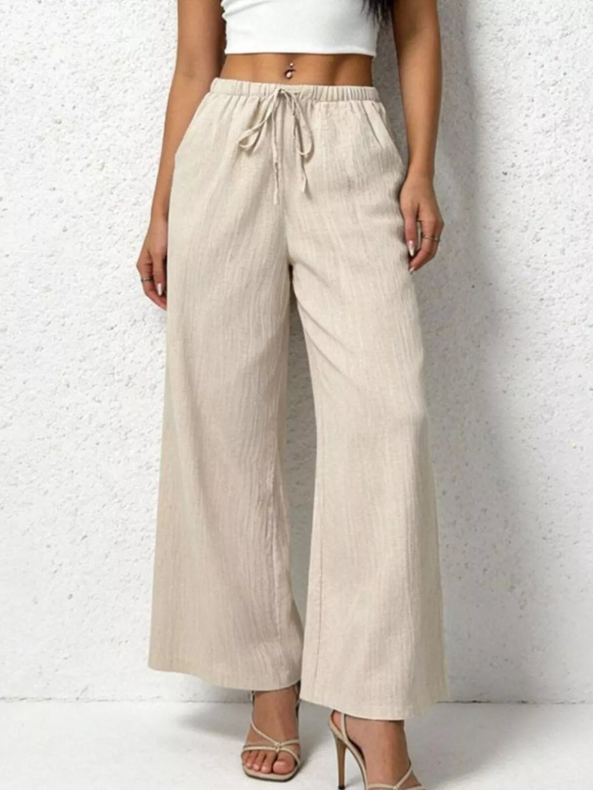Beige wide-leg pants worn by a person on a white background