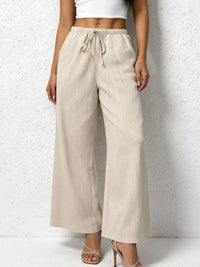 Beige wide-leg pants worn by a person on a white background