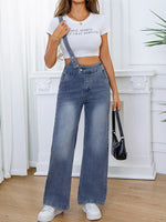 Person wearing a white crop top and blue denim overalls indoors.