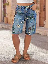 Person wearing floral denim shorts on a street.