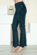 Dark blue jeans worn by a person on a light wooden floor.