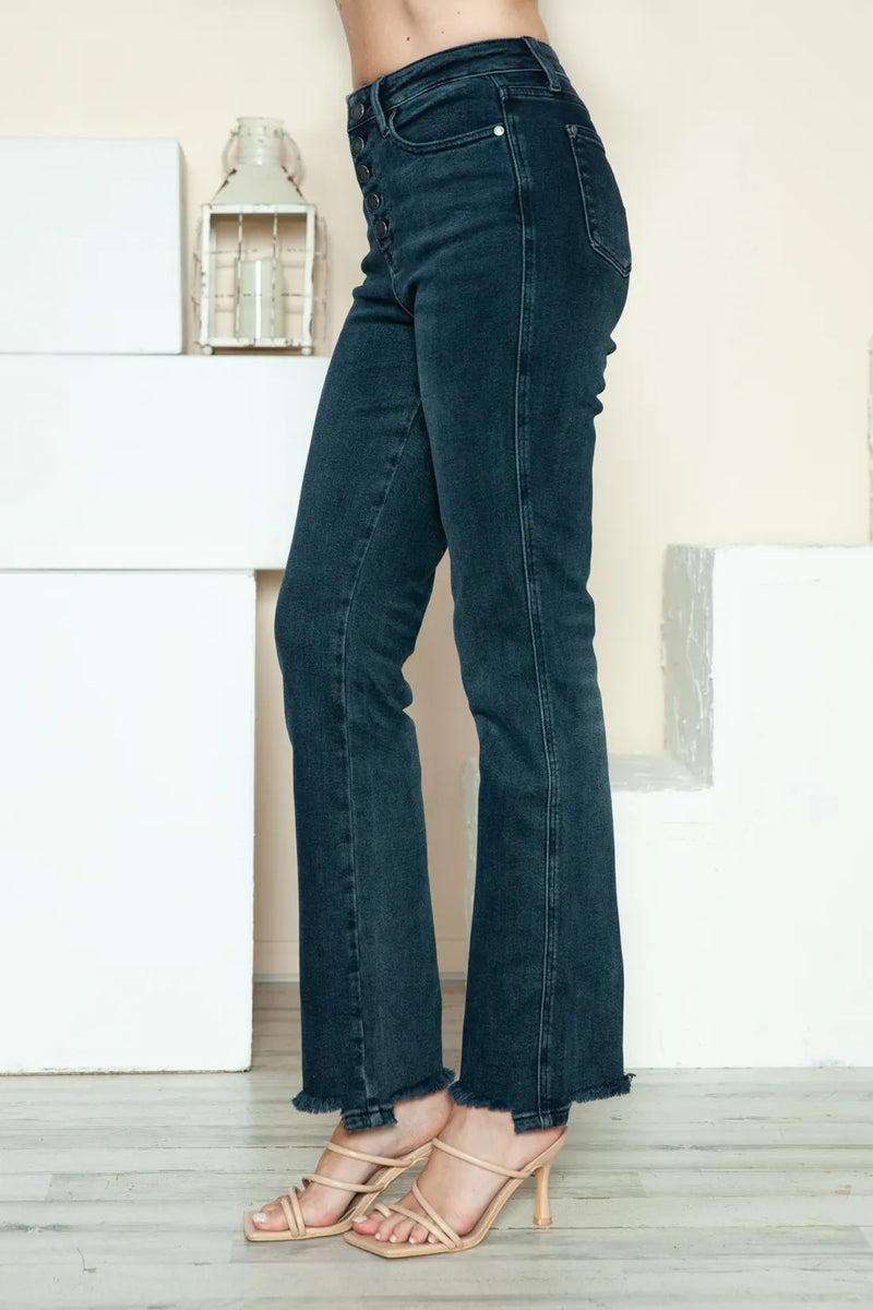 Dark blue jeans worn by a person on a light wooden floor.